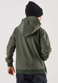 Grøn, vandtæt jakke med hætte, elastiske manchetter og lynlås. Har et logo på ryggen og sidelommer. Bæres med en sort hue.