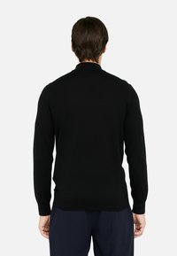 Maglione nero lavorato a maglia con maniche lunghe e scollo rotondo. Realizzato in materiale morbido, presenta una texture liscia e una vestibilità aderente.