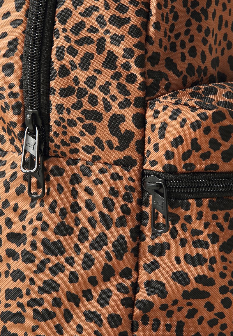 Mochila de estampado de leopardo con fondo marrón y manchas negras. Presenta dos cremalleras negras y una superficie de tela texturizada.