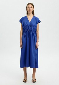 Kleid aus einem Baumwollmischung in Blau mit V-Ausschnitt, kurzen Ärmeln, elastischem Bund und fließendem Rock. Minimalistisches Design ohne sichtbare Muster.