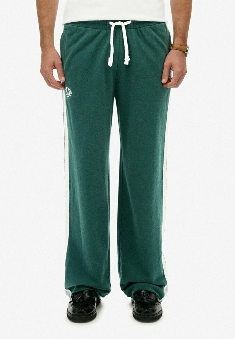 Groene sweatpants met een trekkoord in de taille, witte zijstrepen, losse pasvorm en een klein logo op de linker dij. Gemaakt van zachte stof.