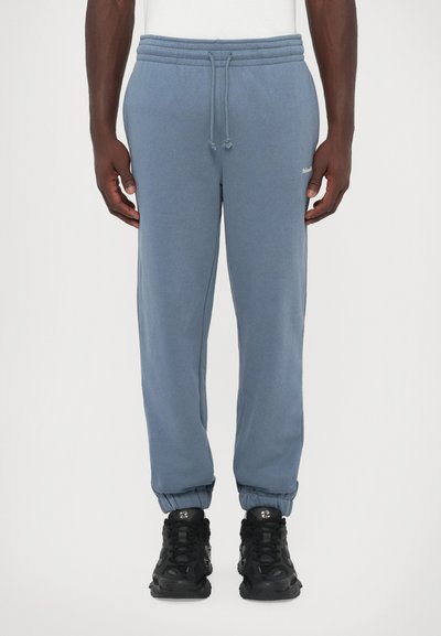 Light blue sweatpants with an elastic waistband and drawstring. Ribbed cuffs at the ankles. Small logo detail near the hip.