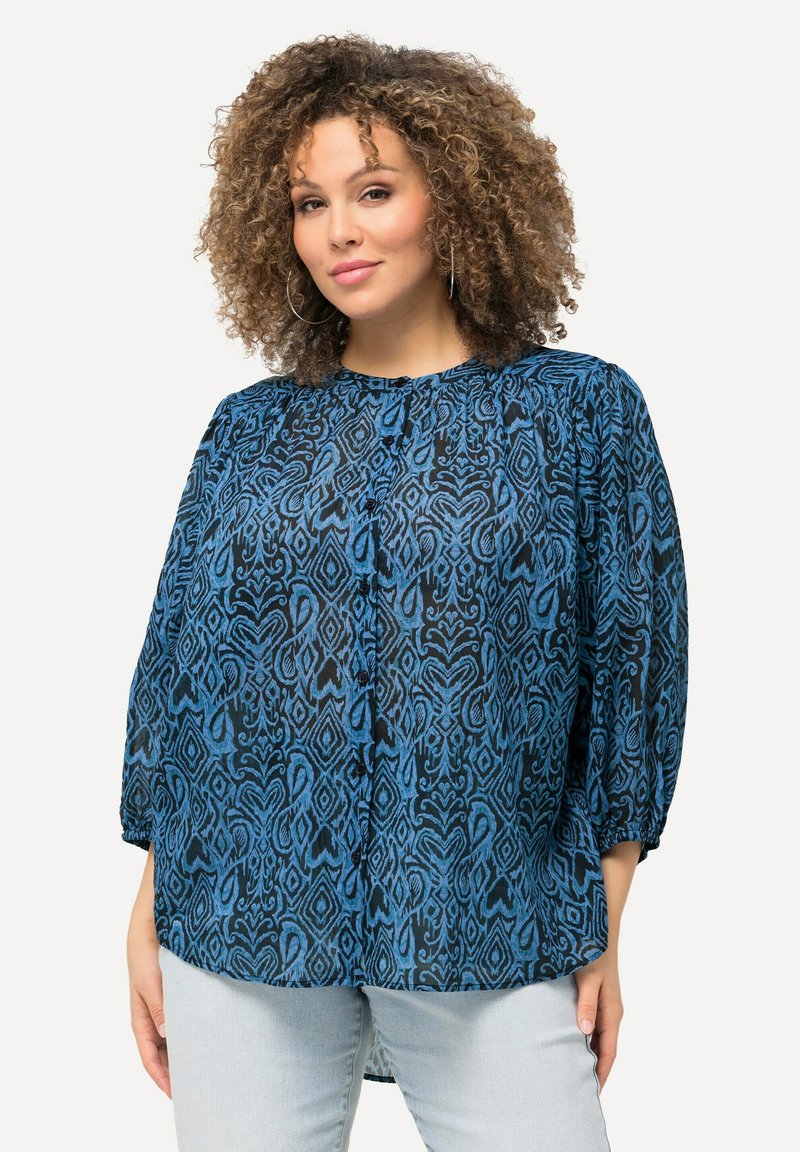 Blusa blu a fantasia con vestibilità ampia, scollatura rotonda e maniche a sbuffo. Il design presenta forme astratte su uno sfondo nero.