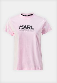 Camiseta de algodón rosa con mangas cortas y cuello redondo. Presenta el logotipo en negro "KARL LAGERFELD" y un gráfico distintivo del personaje en la parte delantera.