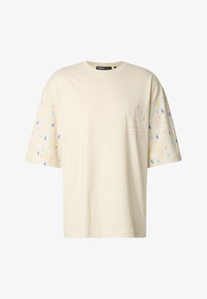 Kermanvalkoinen lyhythihainen t-paita, jossa värikkäitä nonparelleja hihoissa ja donitsikuva edessä. Kevyt puuvillamateriaali.