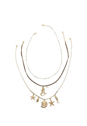 Tri vrstvy náhrdelníkov v zlatom tóne so šarmami s námornou tematikou vrátane morských hviezd, mušlí, morskej panny, rýb a detailov mušlí na bielom pozadí.