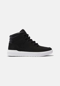 Baskets montantes noires avec col matelassé et lacets noirs, dotées d'une semelle blanche et d'un logo embossé discret au talon.