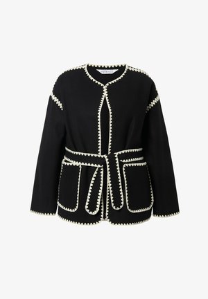 Sort langærmet jakke med hvid bølget kant, forlommer og et matchende bælte bundet om taljen.