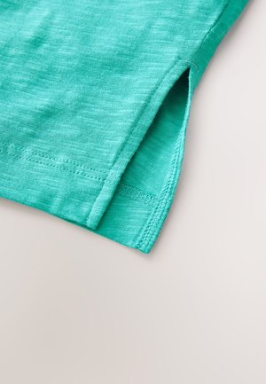 Turkusowa bawełniana tkanina o melanżowej fakturze. Posiada boczne rozcięcie i starannie wykończone krawędzie. Miękki, lekki i przewiewny materiał.