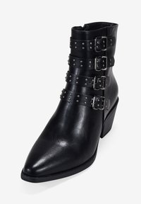 Bottine noire en cuir, avec trois accents de sangles ornées de boucles et d'étoiles argentées, bout pointu et petit talon carré.