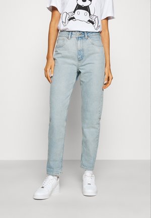 Hellblaue High-Waist-Jeans mit geradem Bein, ausgestattet mit einem Knopfverschluss und fünf Taschen. Kombiniert mit weißen Sneakers.