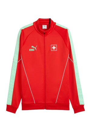 Rote Puma Zip-up-Jacke mit hellgrünen Streifen an den Ärmeln, weißen Paspel-Details, Schweizer Flaggen-Aufnäher und "KING"-Schriftzug mit Puma-Logo auf der Brust.