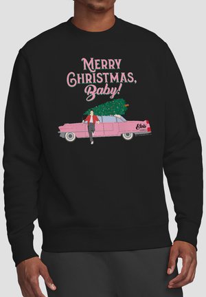 Man wearing black sweatshirt with pink car carrying Christmas tree and text "Merry Christmas, Baby!" in festive font.