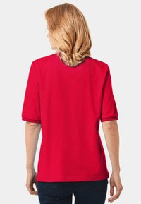 Rode katoenen T-shirt met korte mouwen, een ronde hals en een rechte snit. Stof lijkt zacht met een gladde textuur. Achteraanzicht.