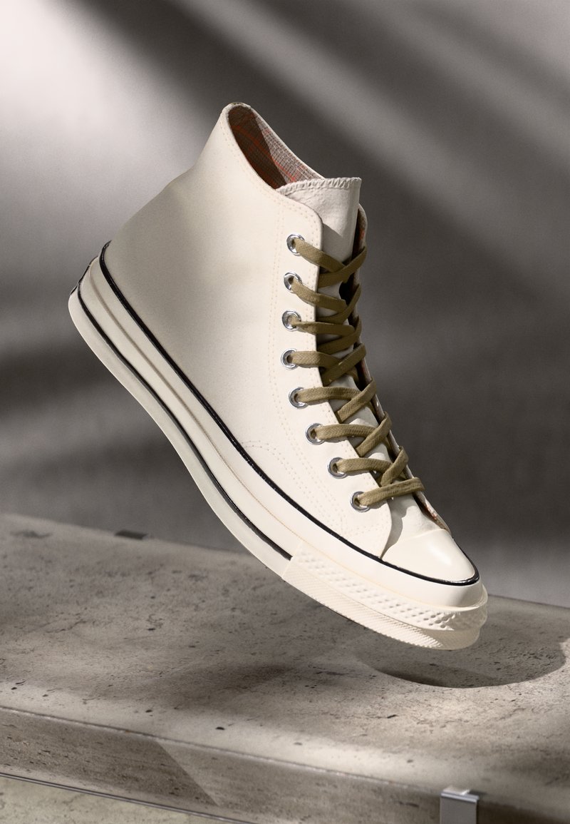 Zapatilla alta en lona color blanco roto con cordones en verde oliva, punta reforzada, raya de acento negra y forro a cuadros.