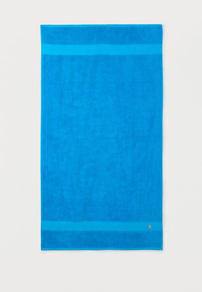 Serviette rectangulaire bleu vif avec deux bandes horizontales bleu clair près des bords et petit logo brodé orange en bas à droite.