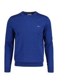 Maglione blu lavorato a maglia con maniche lunghe e polsini a costine; presenta un piccolo logo sul petto. Design classico con scollo rotondo. Texture morbida.