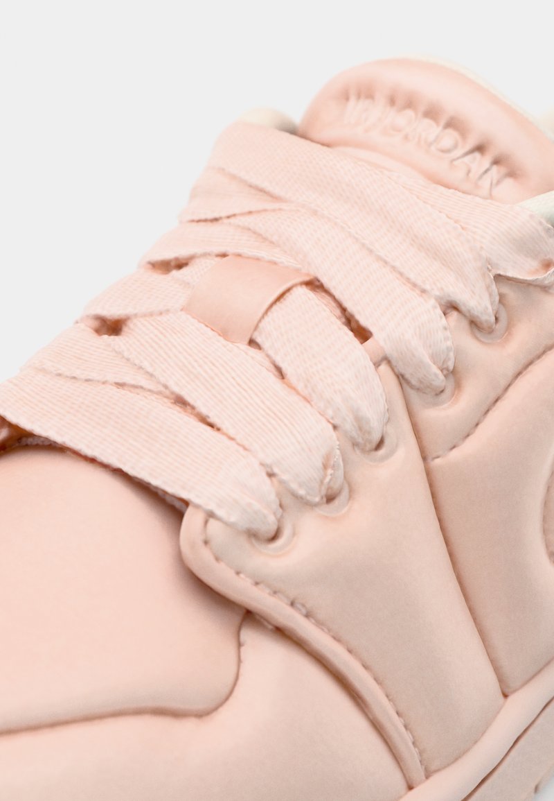 Zapatilla rosa claro con un upper sintético suave, cordones de tela y una puntera redondeada. La marca está grabada en la lengüeta.