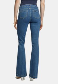 Jeans blu a zampa d'elefante con vita media, dettagli delle cuciture delle tasche posteriori e una texture leggermente sbiadita. L'orlo è grezzo e leggermente sfibrato.