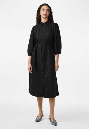 Sort skjorte kjole med krave, lange puffede ærmer og taljebånd. Fremstillet af tekstureret stof, med en længde til midt på læggen.