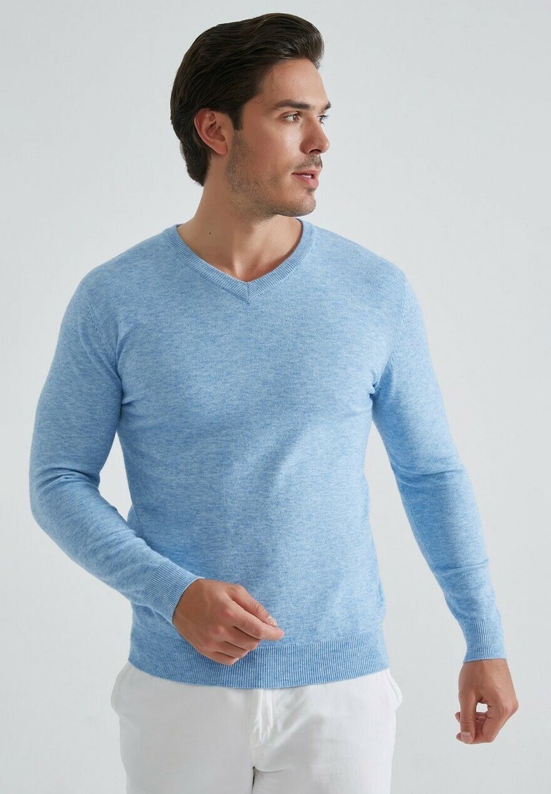 Pull en v léger bleu en tissu texturé doux. Style ajusté avec des manches longues et des poignets et un ourlet côtelés.