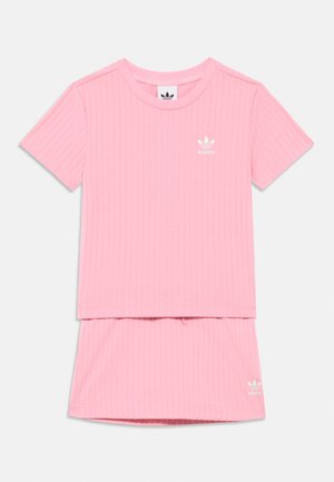 Roze geribd Adidas shirt met korte mouwen en bijpassende rok, met wit logo op de linkerborst en linksonder aan de zoom.