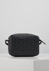 Czarna prostokątna torba z wytłoczonym wzorem zawierającym litery "CK". Wyposażona w dwie boczne rączki oraz zamek błyskawiczny. Teksturowana powierzchnia.