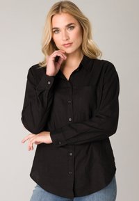 Zwarte lange mouwen shirt met een button-down kraag, voorzak en klassieke pasvorm. Gemaakt van gestructureerde stof met een gladde afwerking.