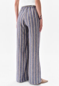 Blauw en beige gestreepte wijde broek met een elastische tailleband en zachte textuur, met een losse pasvorm en subtiele stikdetails.