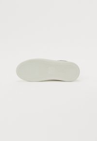 Shoe sole in white rubber with textured herringbone pattern. Clean design, slight arch, and logo detail near the heel, flat surface.