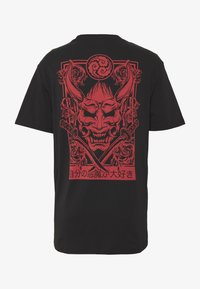 Svart t-shirt med en röd japansk demonmask, korsade svärd, dekorativa virvlar och japansk text längst ner på baksidan.
