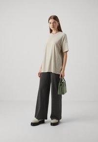 Bež oversize t-särk, hallid triibulised laiad püksid ja roheline kott. Paksude kreemikate platvormkingadega, lühikeste varrukatega, minimalistlik disain.