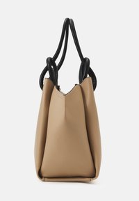 Torebka tote w kolorze brązowym z teksturowanym wykończeniem i dwoma czarnymi, okrągłymi uchwytami. Torebka ma luźny kształt i otwartą górę.