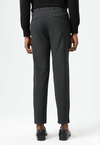 Graue, maßgeschneiderte Hosen mit glatter Textur, einem schlanken Schnitt, Gesäßtaschen und einem Saum, der knapp über den Schuhen sitzt.