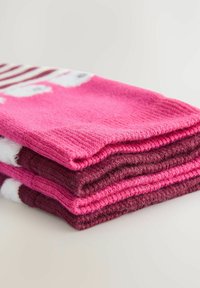 Fyra staplade strumpor, med en blandning av rosa och vinröda färger. Randigt mönster på den översta strumpan, mjuk stickad textur och rundade mudd.