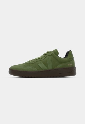 Grüne Wildlederschuhe mit runder Zehenpartie, flacher Gummisohle und Ton-in-Ton-Nähten. Ein Seitenlogo und ein gepolsterter Kragen vervollständigen das Design.