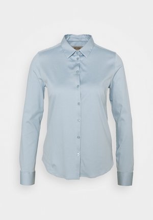 Chemise bleu clair à manches longues avec col et poignets, présentée sur un fond blanc uni.
