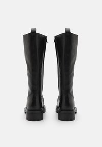 Bottes noires en cuir montantes avec une finition lisse, dotées d'une fermeture éclair à l'arrière et de semelles en caoutchouc noir solides et robustes.