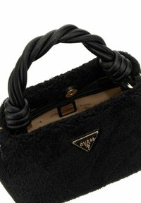 Zwarte pluche handtas met gevlochten handvat, gouden logo-accent, ritssluiting en een gestructureerde afwerking. Binnenkant is tan met een logo-patroon.