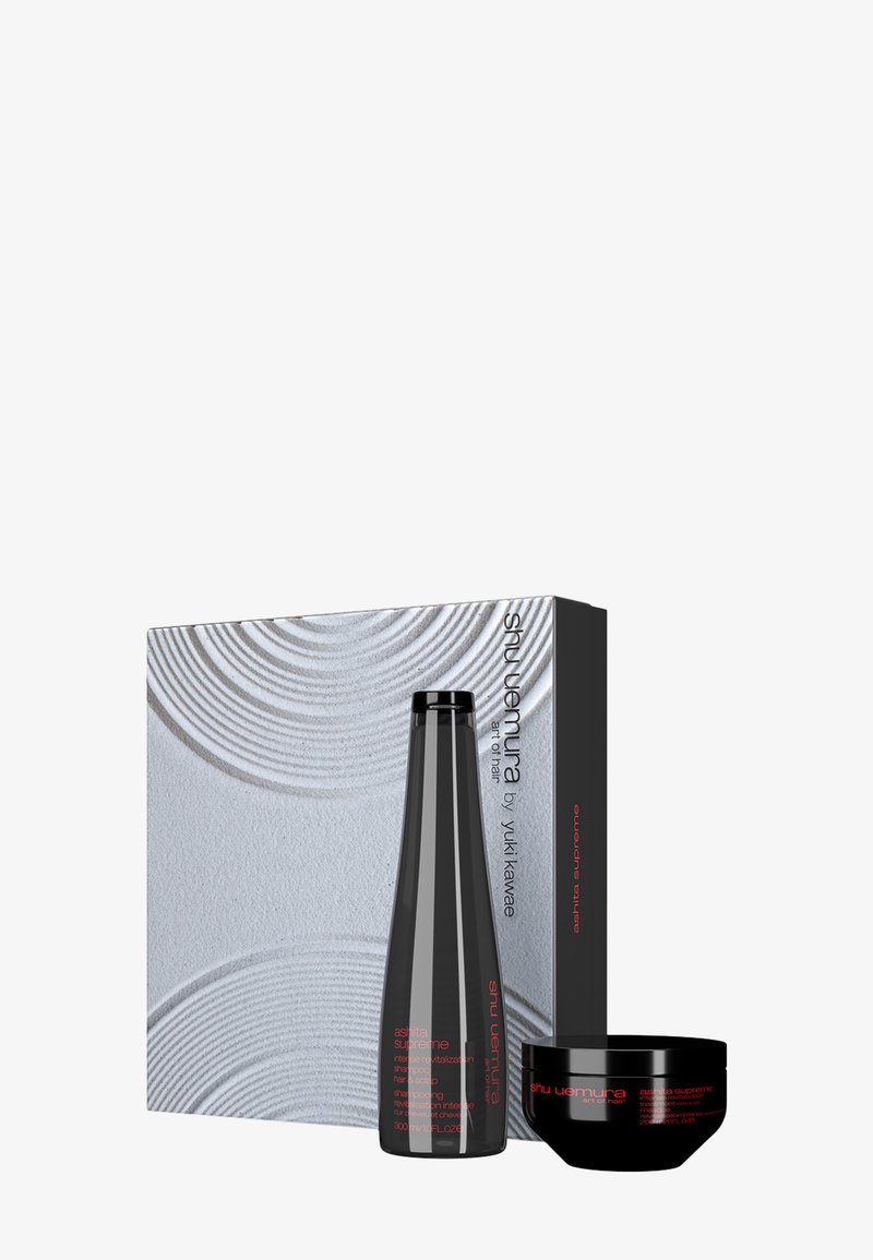 Bottiglia di shampoo nera e barattolo nero, entrambi con testo rosso, accanto a una scatola argentata texturizzata con motivi circolari concentrici.