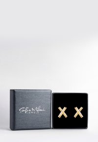 Gouden kruis oorbellen met heldere accenten, tentoongesteld in een zwarte gestructureerde juwelenbox met een logo op de deksel.