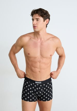 Schwarze Boxershorts mit einem weißen geometrischen Muster, ausgestattet mit einem einfarbigen schwarzen Bund, der mit "BOSS" gekennzeichnet ist. Weicher Stoff mit einer enganliegenden Passform.