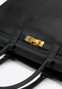 Zwarte leren handtas met een gestructureerde afwerking, voorzien van dubbele handgrepen en een gouden metalen sluiting. Ritsluiting langs de bovenrand.
