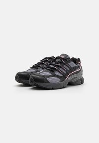 Black and gray athletic shoes featuring mesh panels, pink accents, textured rubber soles, and a layered design with laces.