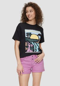 Black cotton t-shirt with colorful beach-themed graphic, paired with light purple denim shorts. Short sleeves and relaxed fit.