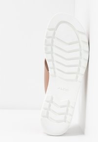 Brun slide sandal med en texturerad ovandel, vit gummiyttersula med ett zigzag-mönster och "ALDO"-logotyp på sulan.