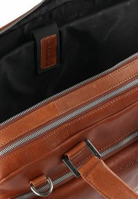 Borsa per laptop in pelle marrone con interno nero, dotata di cerniere argentate, tasche esterne e una tracolla robusta con dettagli in metallo.