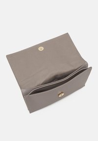 Cartera de tela gris con solapa, que cuenta con un cierre a presión dorado, bolsillos interiores y una textura suave. El diseño abierto muestra la capacidad de almacenamiento.
