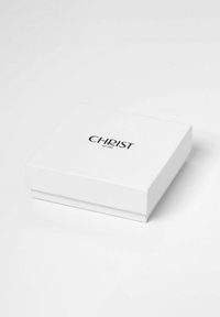 Weißer Karton mit glatter Textur, versehen mit einem schwarzen Logo, das "CHRIST est. 1863" in der Mitte des Deckels zeigt.