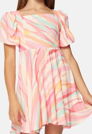 Meisje draagt een korte jurk met pofmouwen en abstracte strepen in pastelroze, oranje, geel en mintgroen.